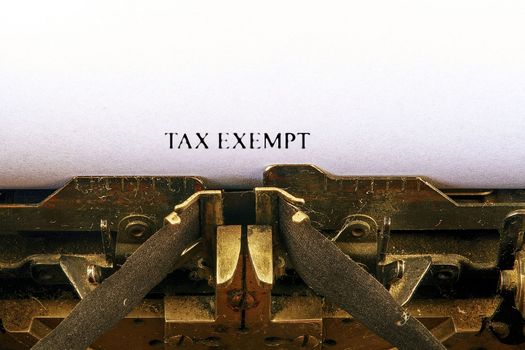 Closeup on vintage typewriter. Front focus on letters making TAX EXEMPT text. Business concept image with retro office tool.