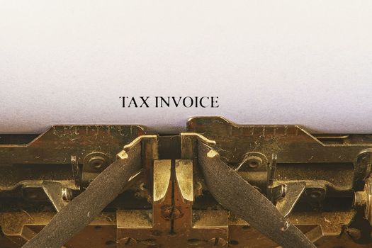 Closeup on vintage typewriter. Front focus on letters making TAX INVOICE text. Business concept image with retro office tool.