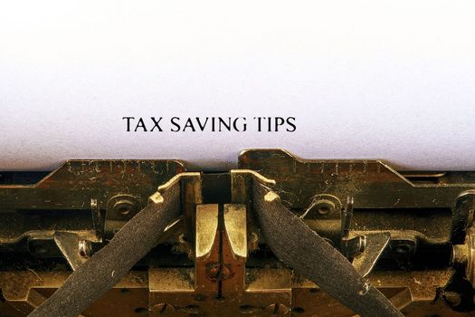Closeup on vintage typewriter. Front focus on letters making TAX SAVING TIPS text. Business concept image with retro office tool.
