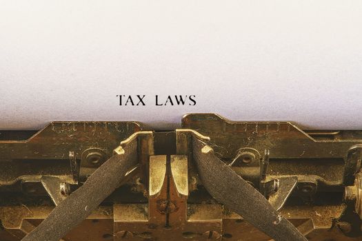 Closeup on vintage typewriter. Front focus on letters making TAX LAWS  text. Business concept image with retro office tool.