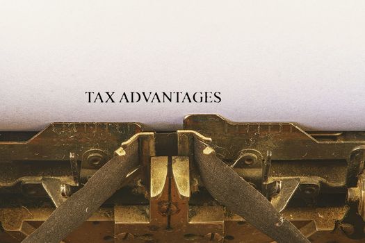 Closeup on vintage typewriter. Front focus on letters making TAX ADVANTAGES text. Business concept image with retro office tool.