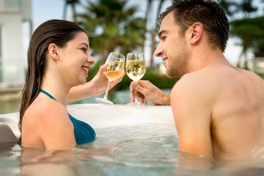 Young couple inside a jacuzzi and toasting 