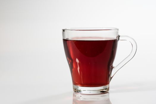 Tea in a glass on a white background. Green or fruit tea. Glass of white glass