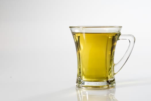 Tea in a glass on a white background. Green or fruit tea. Glass of white glass