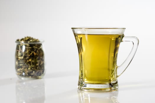 Tea in a glass on a white background. Green or fruit tea. Glass of white glass