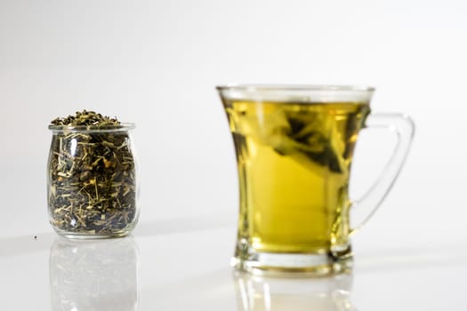 Tea in a glass on a white background. Green or fruit tea. Glass of white glass