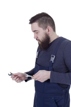 Bearded young man with a wrench in a working overall