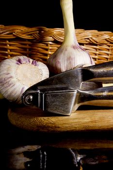 Garlic press and cloves of garlic laid on a wooden table background