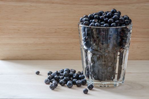 Blueberries in a glass with scattered berries. Vitamin charge for long day