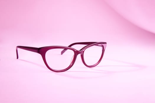 Advertising studio shot of pink glasses with long shadow at pink background.