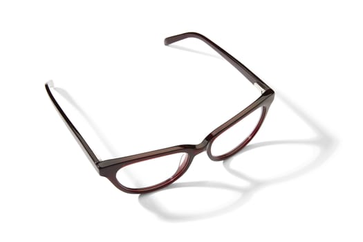 Studio shot of pair of burgundy eyeglasses on white background with shadow.