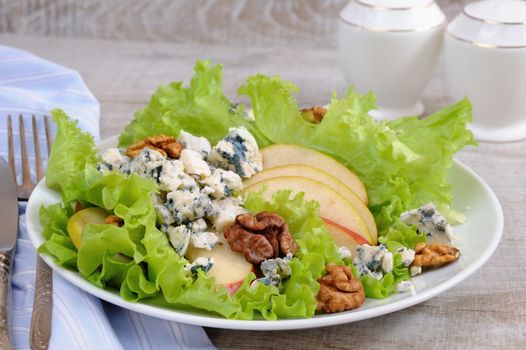 A light lettuce salad with pear slices, gorgonzola pieces and walnut seasoned with olive oil