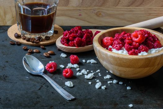 Tasty breakfast with cottage cheese, raspberries and cup of coffee. Scattered berries and grains of curd