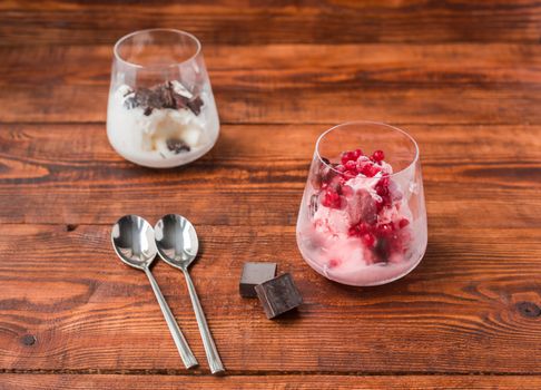 Two portions of vanilla and strawberry ice cream in glass on wooden table