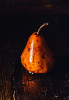 Golden Pear with Drops on Surface on Table. Vertical.