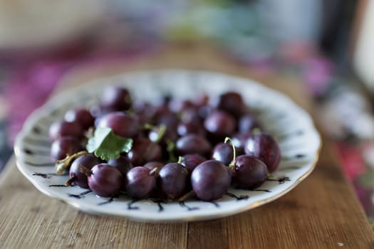 purple ripe gooseberry in a plate, soft focus