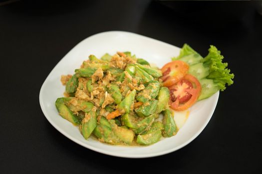 Chinese gourd menu, stir fried with eggs against a black background.