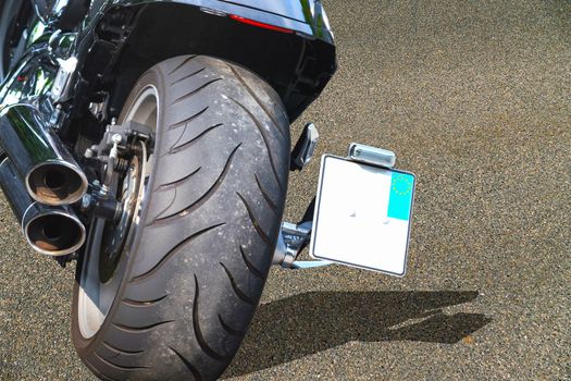 Close up of a large tire of a modern motorcycle parked.