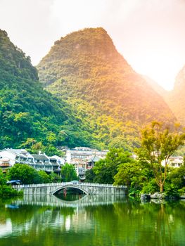 Small bridge over water and green peaks at Yangshuo, Guangxi Province, China.