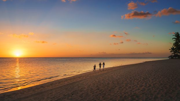 Thtree silhouette running on the beach at sunset in Mauritius.