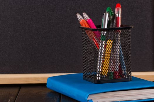 Stationery: pens, pen holder, diary on a black background