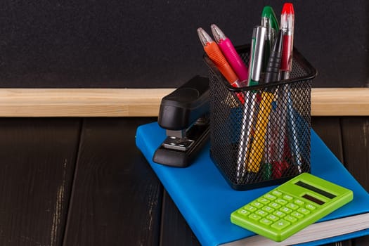 Stationery: pens, pen holder, diary on a black background