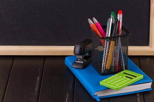 Stationery: pens, pen holder, diary on a black background