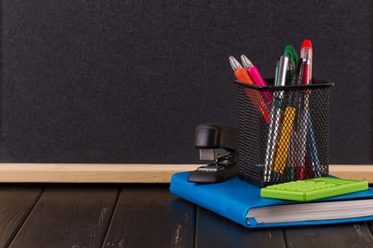Stationery: pens, pen holder, diary on a black background