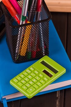 Stationery: pens, pen holder, diary on a black background