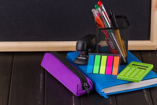 Stationery: pens, pen holder, diary on a black background