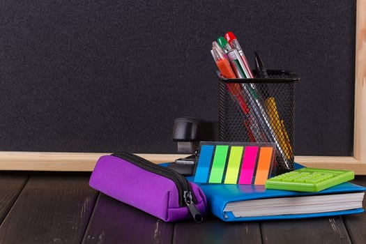 Stationery: pens, pen holder, diary on a black background