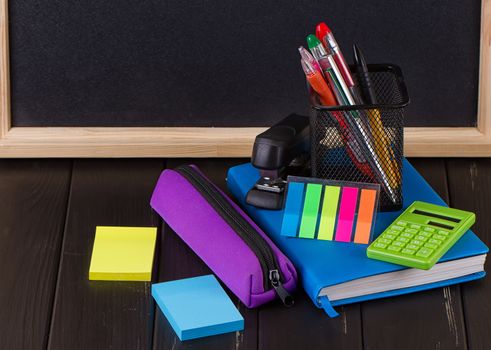 Stationery: pens, pen holder, diary on a black background