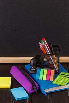 Stationery: pens, pen holder, diary on a black background