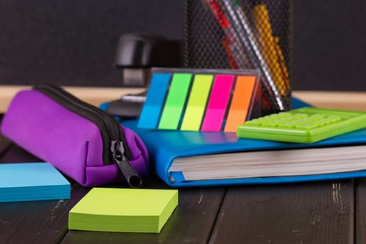 Stationery: pens, pen holder, diary on a black background