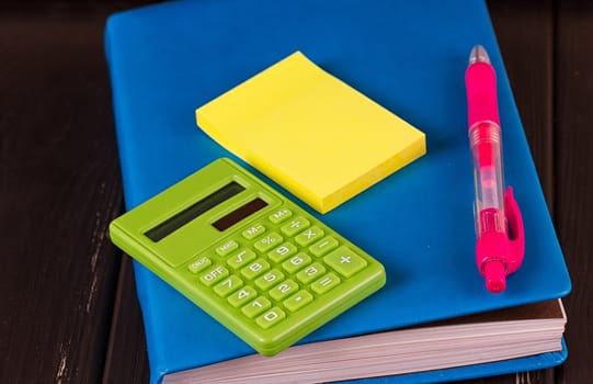 Stationery: pens, pen holder, diary on a black background