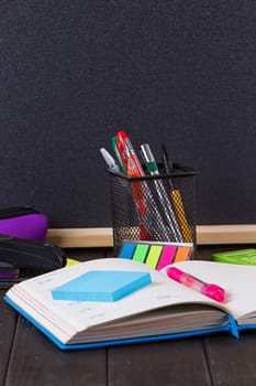 Stationery: pens, pen holder, diary on a black background