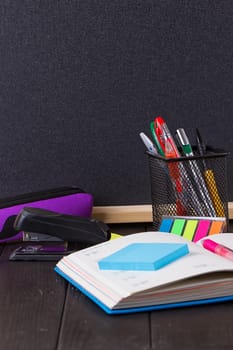 Stationery: pens, pen holder, diary on a black background