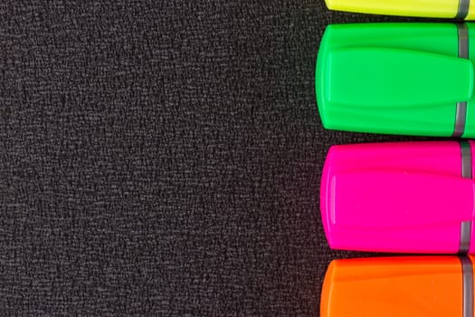 the Colored markers on a black background