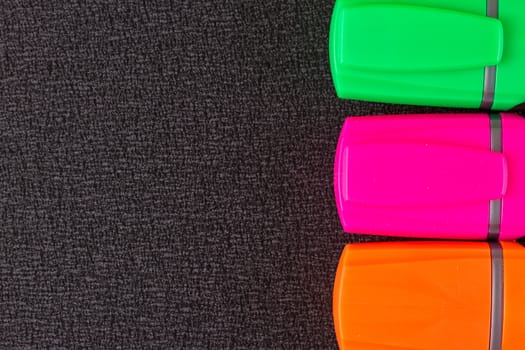 the Colored markers on a black background