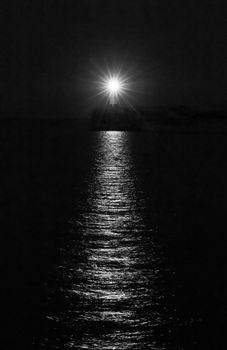 Newhaven Lighthouse on July night, with reflections on the water. Black and white.