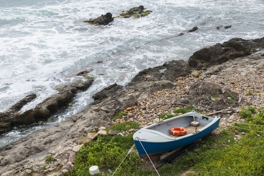 small rowboat is located on the boulders on the coast in Alghero
