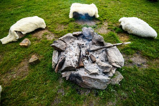 Camp fire made of stone ring, traditional, authentic camp fire , laid out in a circle used bz Alpine herders, next to the fire are logs covered in sheep skin for insulation