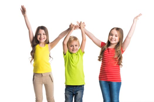 Happy smiling three children in colorful clothes holding raised hands isolated on white background