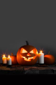 Halloween pumpkin head jack lantern and candles on wooden background