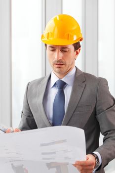 Architects in suit and hardhat working with blueprint in office