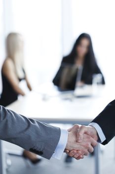 Business people shaking hands in conference room, colleagues on background