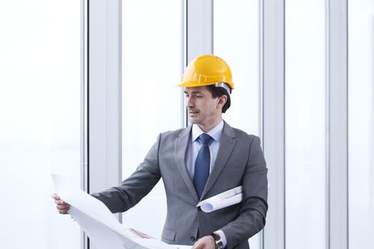 Architects in suit and hardhat working with blueprint in office