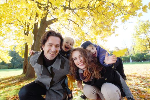 Parents and children having fun in yellow autumn park