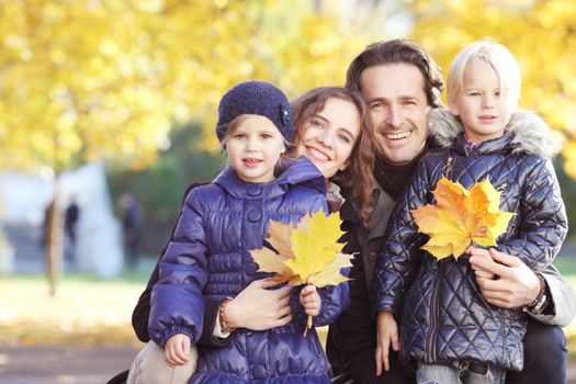 Happy family of parents and two children posing in autumn forest