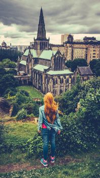 Retro Style Redhead Teenage Girl Looking Out Over Glasgow Cathedral And Skyline With A Rainy Sky